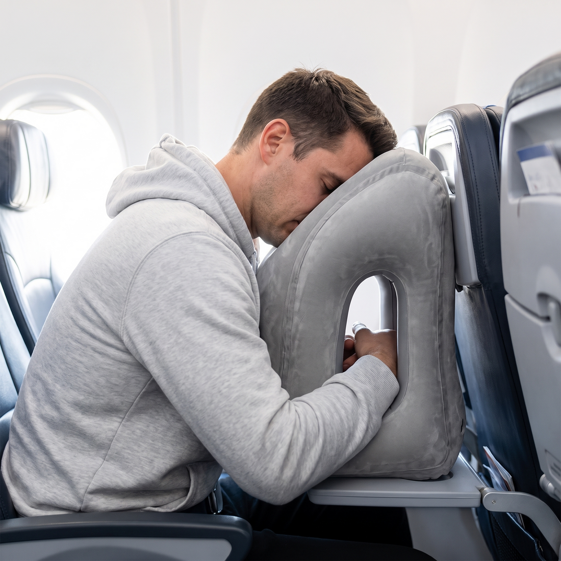 Traveler resting forward on the inflatable pillow during a flight